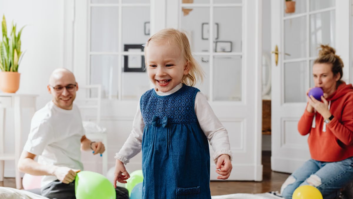 Joyful family playing with balloons indoors, showcasing happiness and bonding.